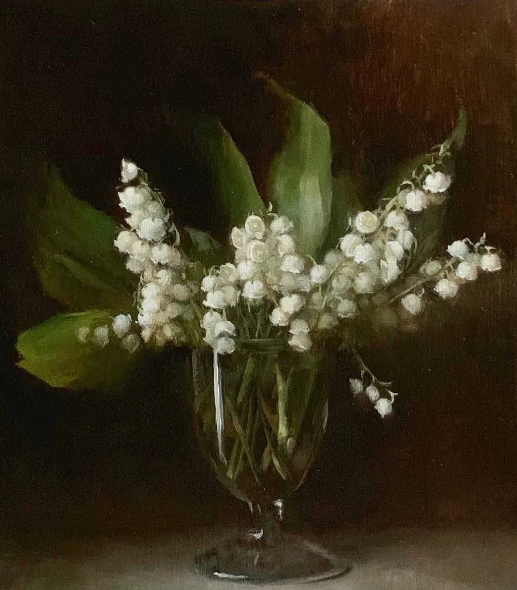 Small bouquet of lily of the valley flowers arranged in a glass vase against a dark background.