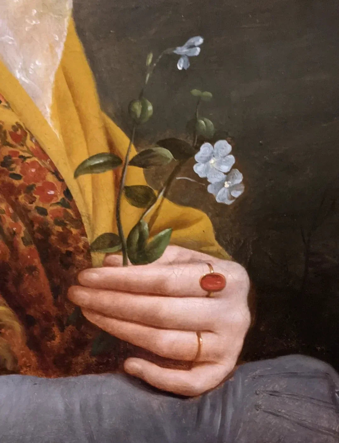 Close-up of a hand holding tiny blue flowers, with a gold ring and warm-toned fabric in a classical painting style