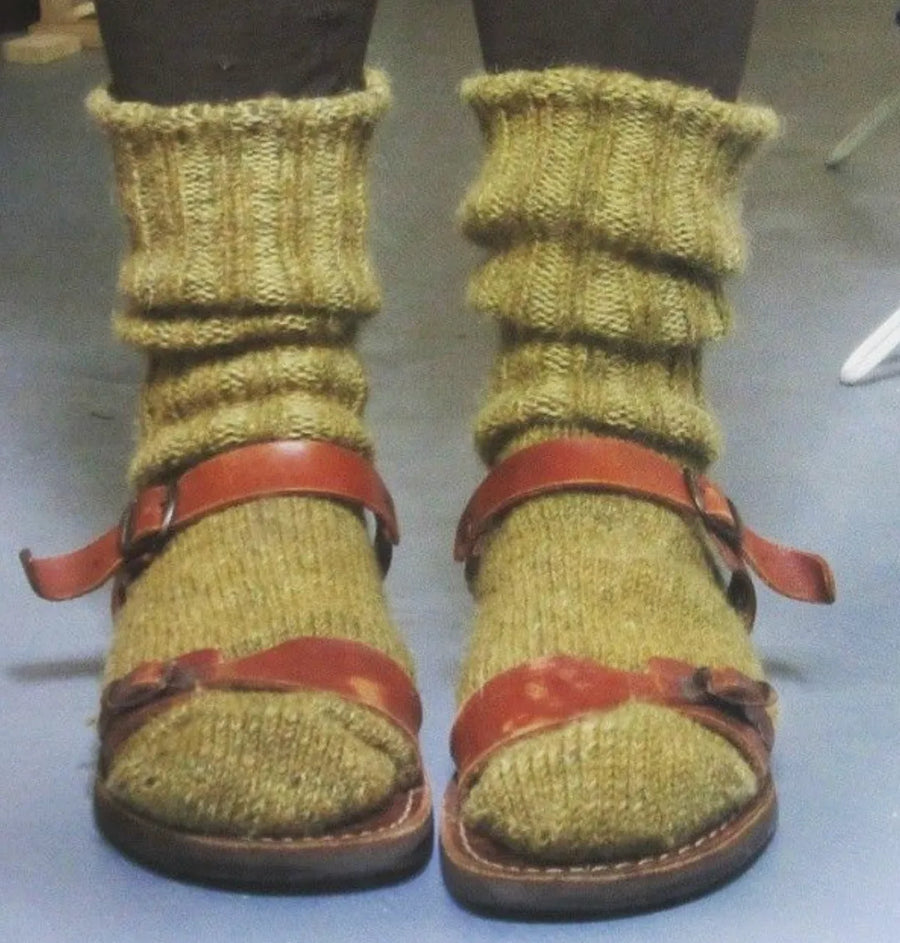 Close-up of chunky knit green socks paired with red strappy sandals.